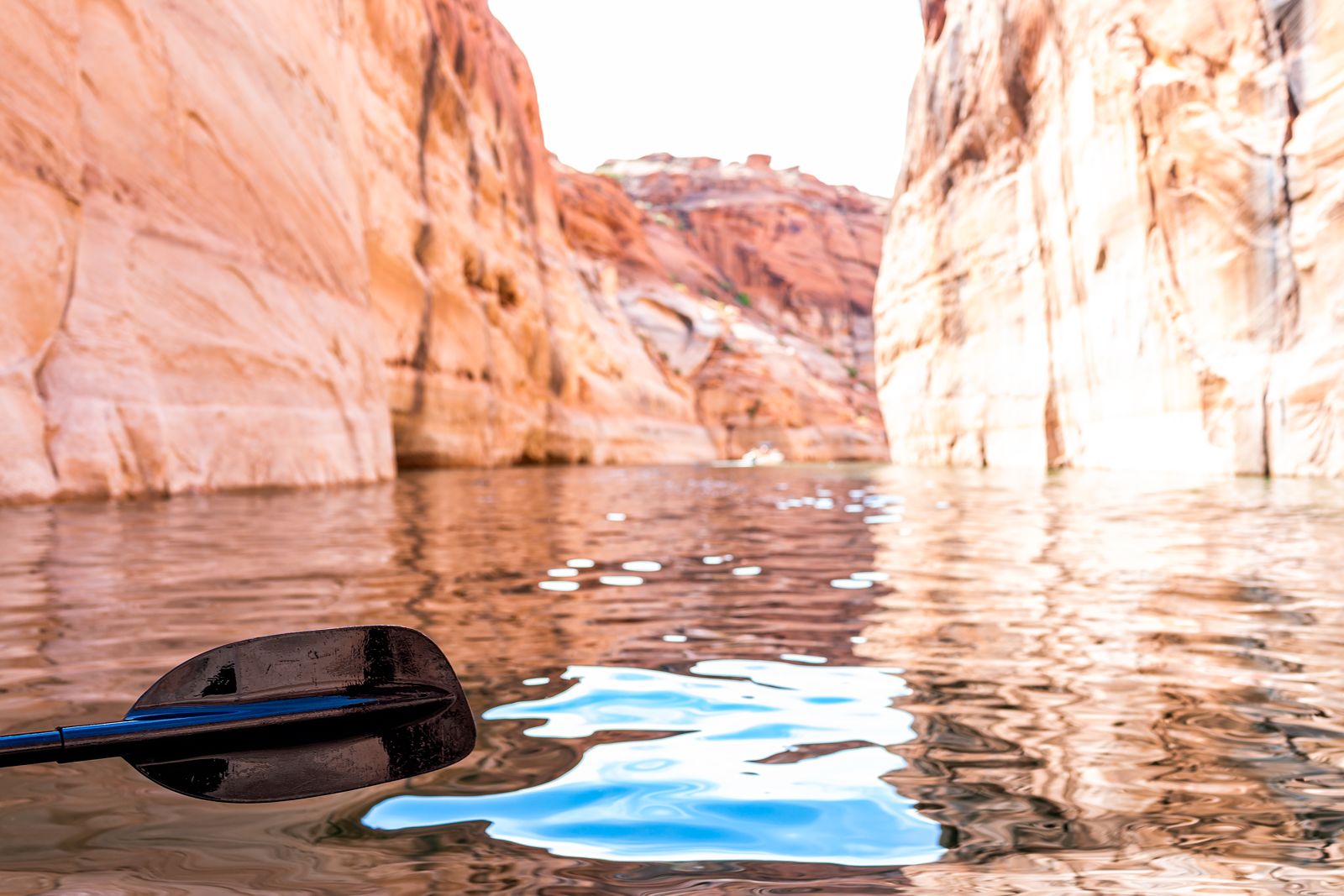 A kayak paddle over calm water between pale sandstone walls on Lake Powell